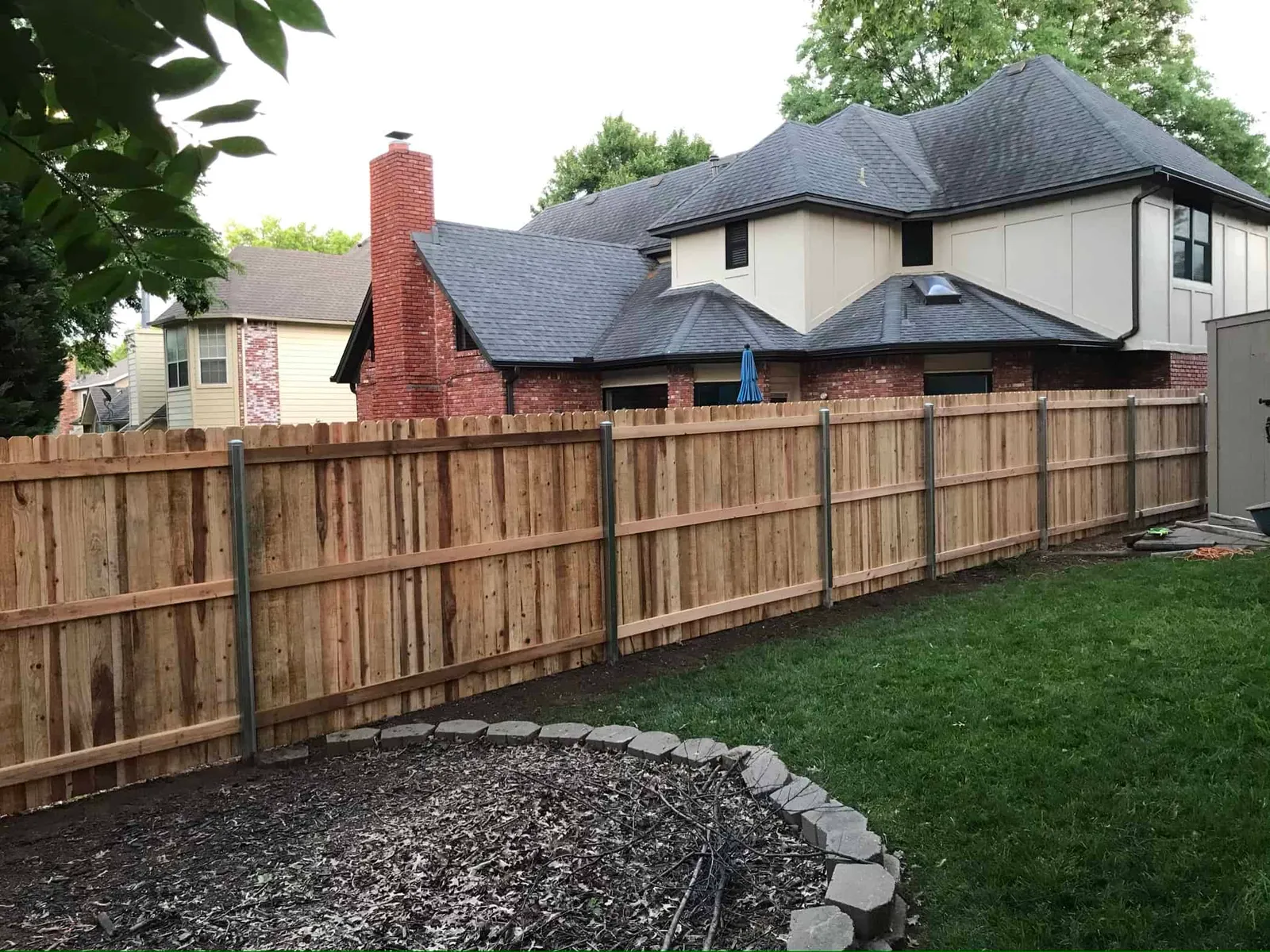 Freshly sealed cedar wood fence in a Tulsa backyard during spring