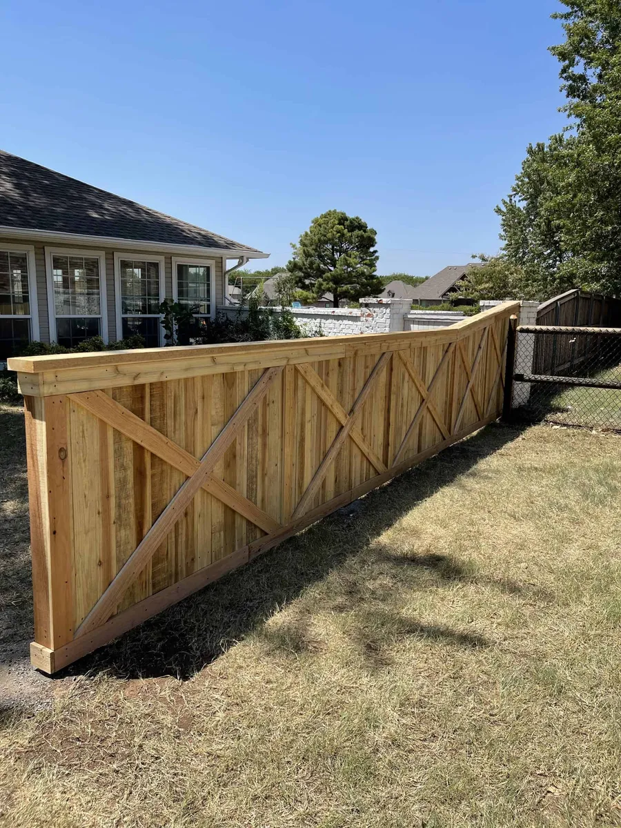 Cedar crossbuck fence against a clear blue sky, a decorative fence style in Tulsa, OK
