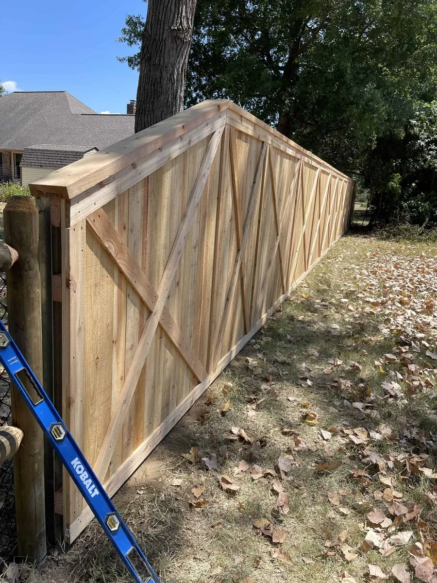 Cedar crossbuck fence with a shaded yard behind it, a decorative fence style in Tulsa, OK