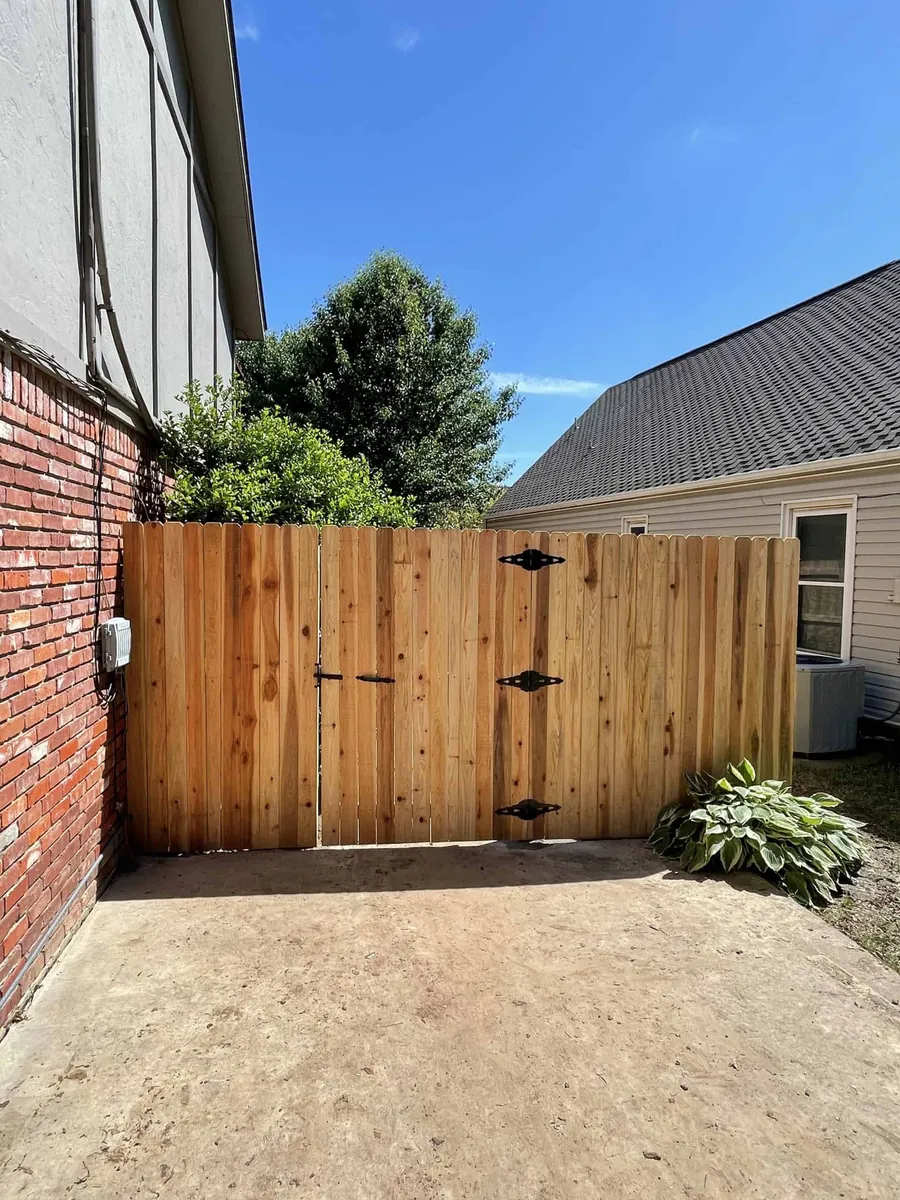 Cedar double drive gate on a concrete pad between two homes, a custom gate in Tulsa, OK