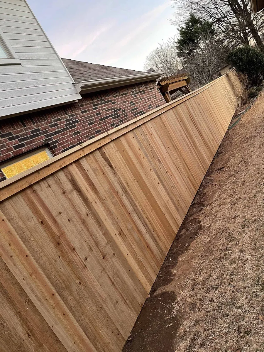 Cedar privacy fence with cap rail behind a brick home, one of many privacy fence styles Tulsa, OK