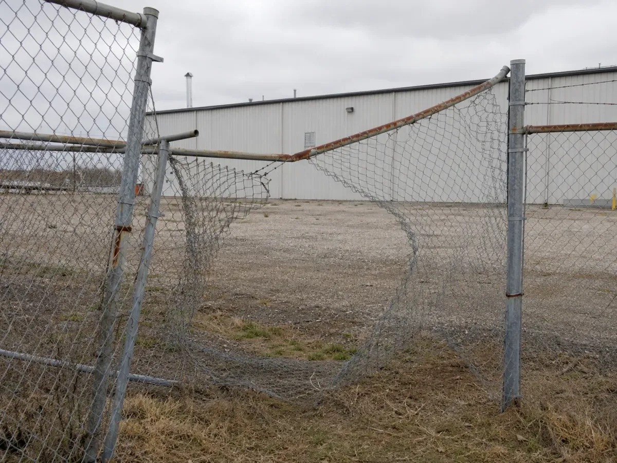 Damaged commercial chain link fence with leaning posts, rust, and sagging mesh, ready for a commercial fence company near me Tulsa, OK